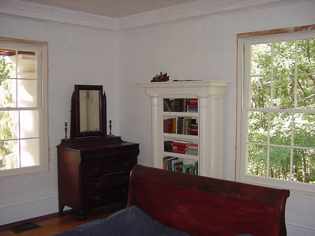 Bedroom with built-in bookcase between two hand-made windows, sleigh bed, antique dresser